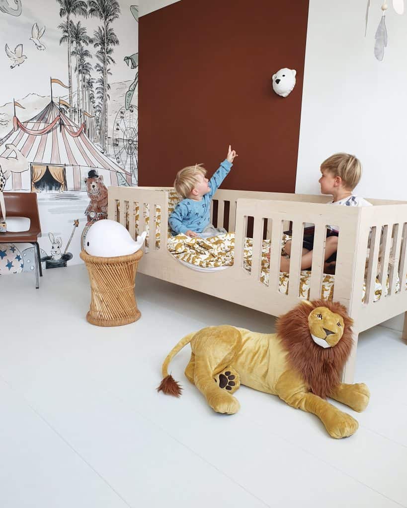 Duas crianças sentadas numa cama, com a luz de presença Bjorn fixada na parede. O Bjorn é uma luz de presença LED com aplique de parede em forma de urso polar da marca Flow Amsterdam