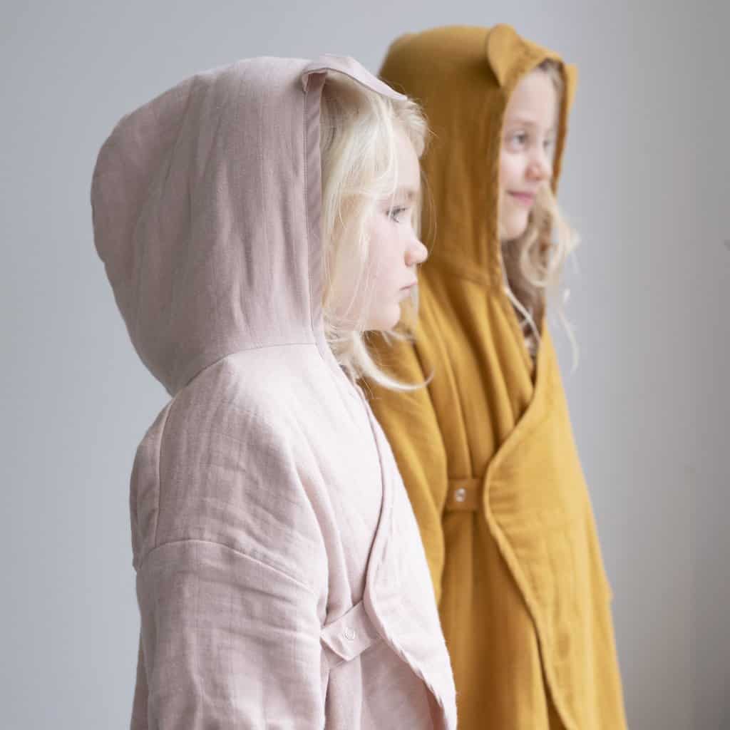 Duas crianças vestidas com o Roupão com capuz na cor ocre e malva da marca Fabelab