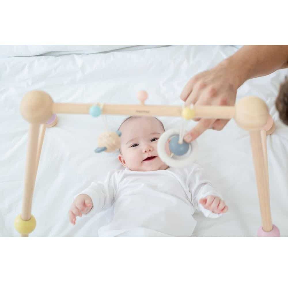 Criança a brincar no elemento decorativos do Ginásio Bebé Madeira - Play Gym Pastel Collection Plan Toys®