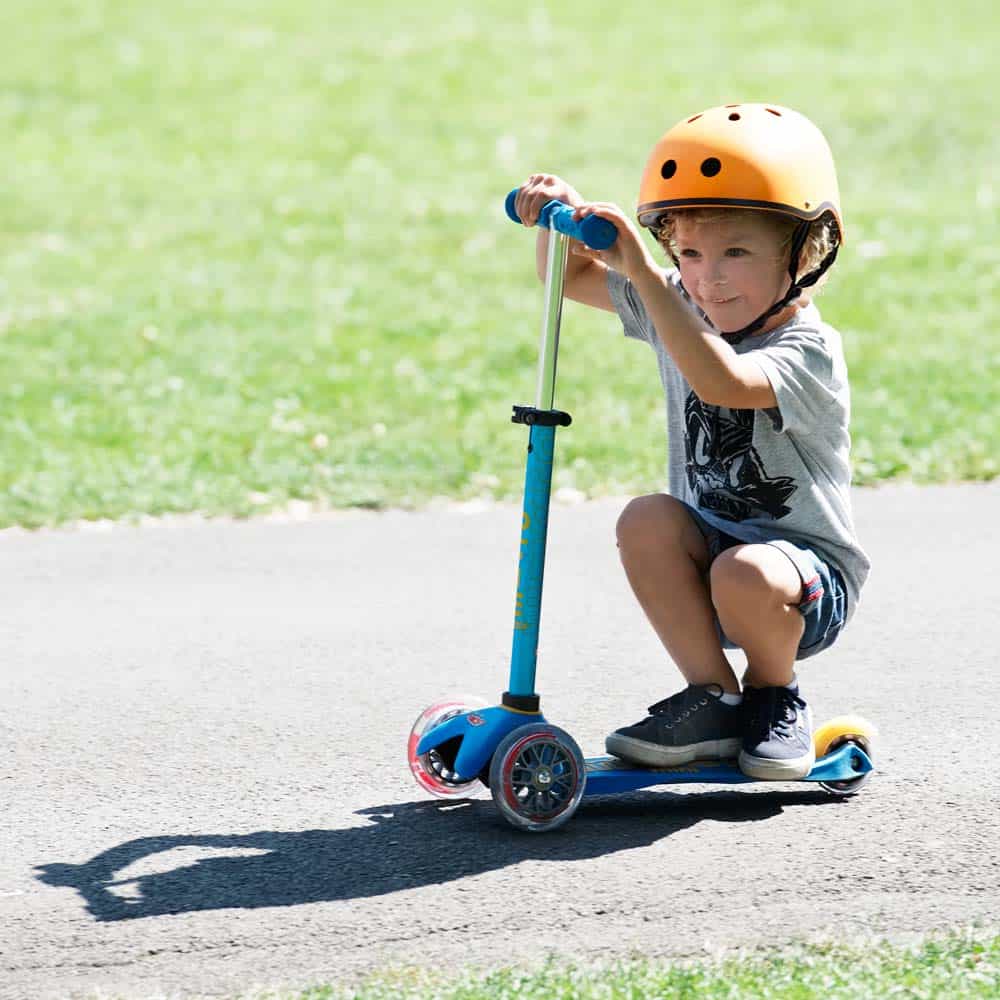 Criança com capacete a andar na Trotinete Mini Micro Deluxe - Azul turquesa