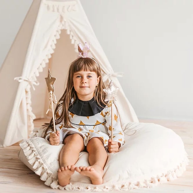 Criança sentada numa Almofada grande para o chão decorada com borlas
