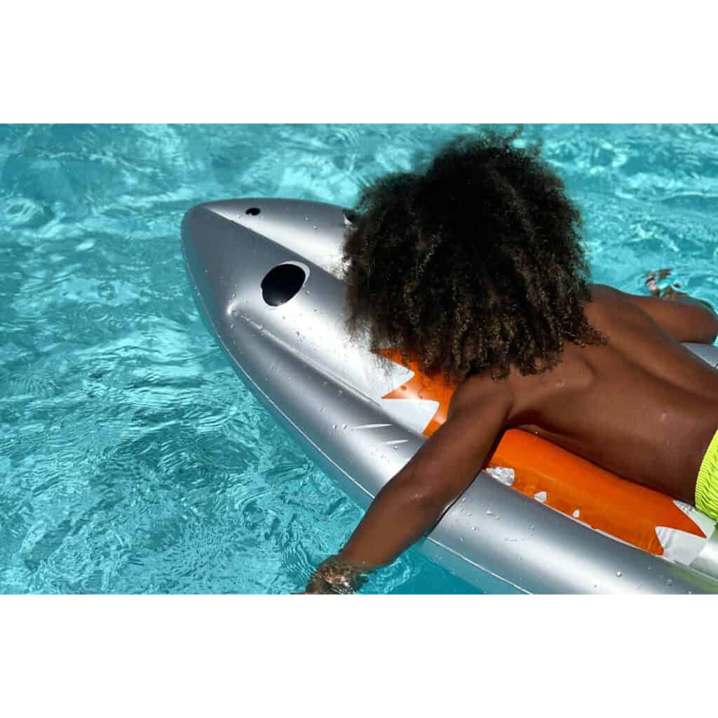 Criança numa piscina a remar na sua A Prancha de Surf Insuflável Sunnylife Tubarão